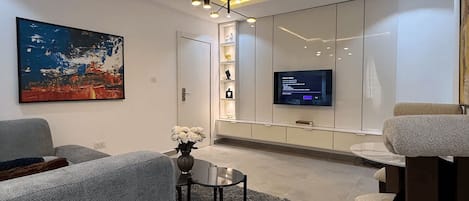 A modern living room with a grey sofa, a coffee table, and a TV mounted on the wall.