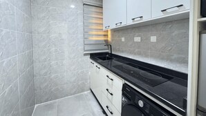 A modern kitchen with a built-in dishwasher, white cabinets, and a black countertop. - Lovely 1-Bedroom in Victoria Island with Pool, Fast Wi-Fi & 24/7 Power (Lagos)