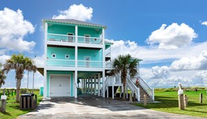 A multi-story building with a white balcony, a covered entrance, and a staircase leading to the upper levels. - Gabriel's Landing - Beachfront 5 bedroom - incredible views, sleeps 18 (Crystal Beach)