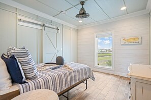A bedroom with a bed, a window with a view, a ceiling fan, and a wall-mounted light fixture. - Gabriel's Landing - Beachfront 5 bedroom - incredible views, sleeps 18 (Crystal Beach)