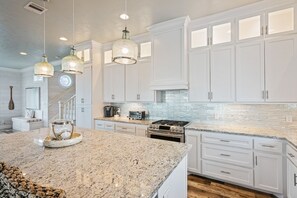 A kitchen with white cabinets, granite countertops, and pendant lighting. - Gabriel's Landing - Beachfront 5 bedroom - incredible views, sleeps 18 (Crystal Beach)