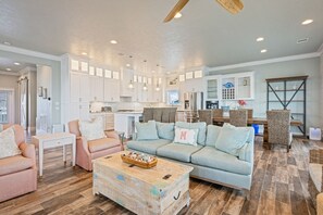 A spacious living area with a light blue sofa, a wooden coffee table, and a dining table with wicker chairs. - Gabriel's Landing - Beachfront 5 bedroom - incredible views, sleeps 18 (Crystal Beach)