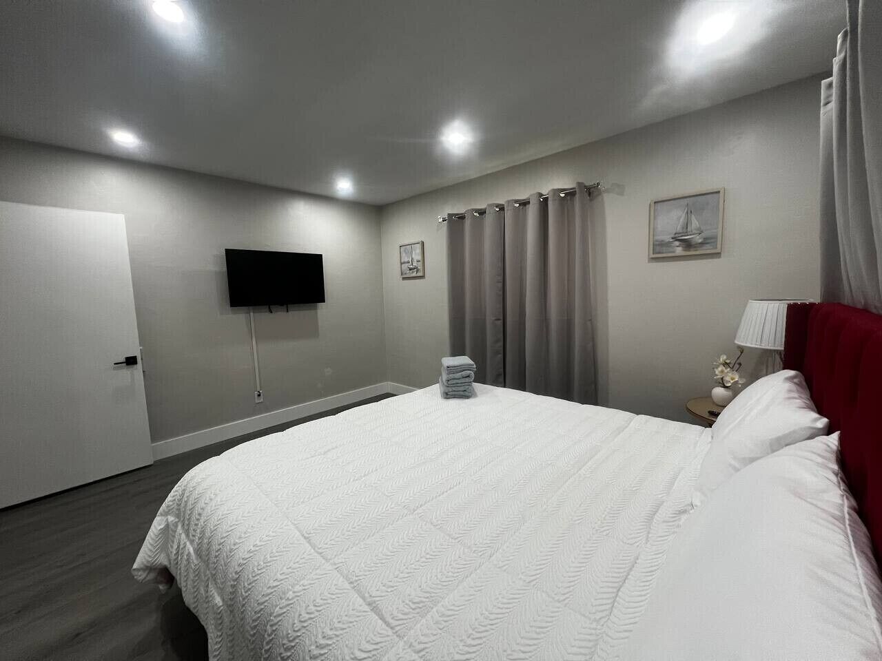 Habitación de hotel con cama, cortinas, televisor de pantalla plana y puerta.