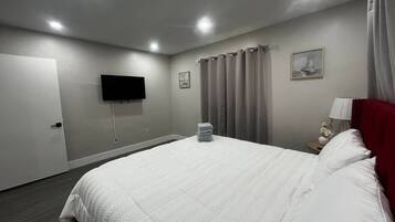 Habitación de hotel con cama, cortinas, televisor de pantalla plana y puerta.
