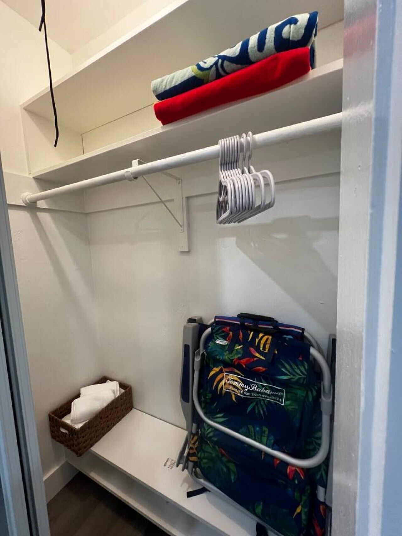 A bathroom with a towel rack, a basket with a towel, and a toiletry bag.