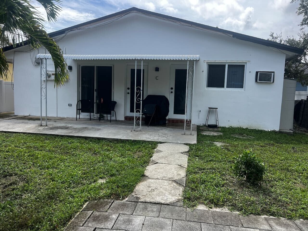 A single-story house with a covered porch, a small garden, and a paved driveway.