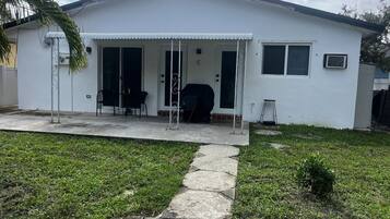 A single-story house with a covered porch, a small garden, and a paved driveway.