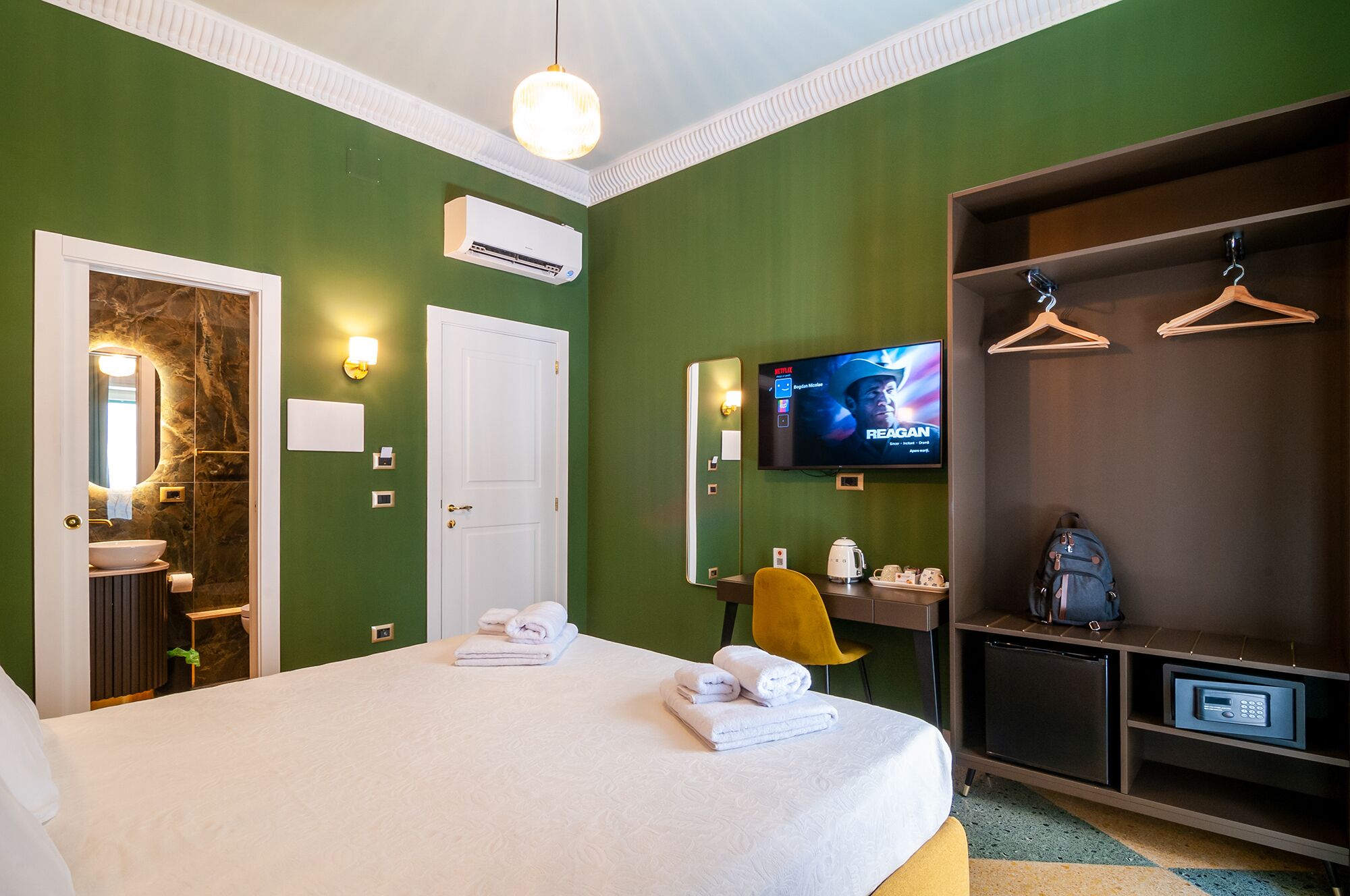 Quarto de hotel com cama, televisão, armário e banheiro.