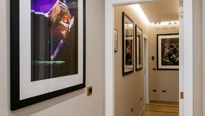 A hallway with framed artwork on the walls, a carpeted floor, and a door leading to another room. - CasaJammone Up Boutique Rooms (Naples)