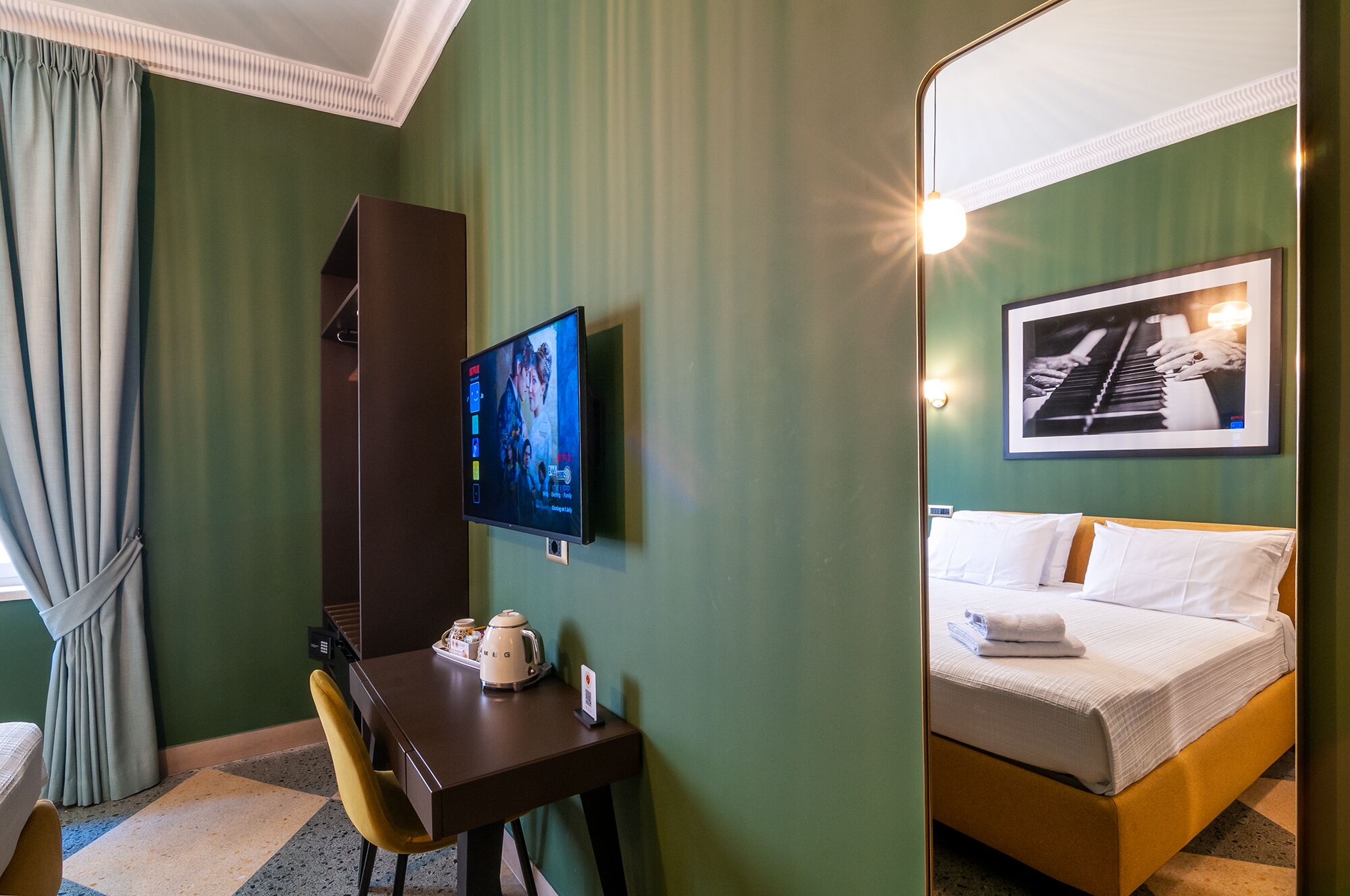 Une chambre d’hôtel avec un lit, un bureau doté d’une bouilloire, une télévision et un tableau encadré au mur.
