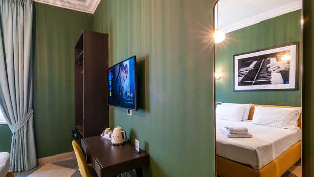 A hotel room with a bed, a desk with a kettle, a television, and a framed picture on the wall. - CasaJammone Up Boutique Rooms (Naples)