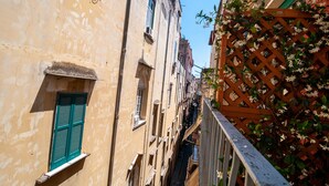 A narrow alleyway between buildings with a wooden lattice fence on one side and a building with a green shutter. - CasaJammone Up Boutique Rooms (Naples)