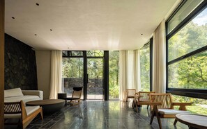 A modern interior with a stone wall, a sofa, a coffee table, and a seating area with chairs. - Qingcheng Moutain Boarding Home stay (Chengdu)