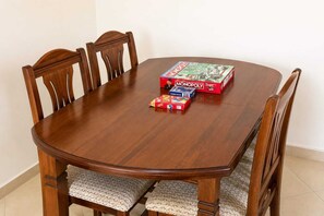 Ein Holzespeisesaal mit vier Stühlen, einem Monopoly-Spiel und einer Poker Route Spielbox.