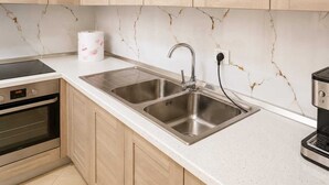 A kitchen with two stainless steel sinks, a built-in oven, and a marble backsplash. - Nilvan Apartment heart of Tirana (Tiranë)