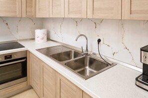 Eine Küche mit zwei Edelstahl-Spülen, einem eingebauten Ofen und einer Marmor-Spritzschutzwand.
