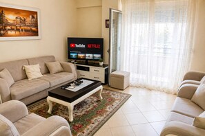 Ein Wohnzimmer mit Sofa, Couchtisch und einem Flachbildfernseher, der die Logos von YouTube und Netflix zeigt.