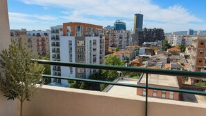 A balcony with a potted plant, overlooking a cityscape with various buildings. - Nilvan Apartment heart of Tirana (Tiranë)