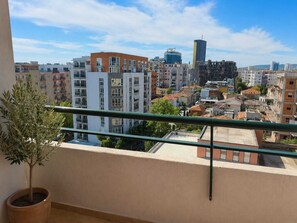 Ein Balkon mit einem Blumentopf, mit Blick auf eine Stadtlandschaft und verschiedene Gebäude.