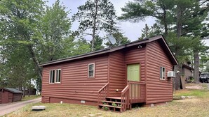 Eine Holzhütte mit Veranda, einer grünen Tür und einer Satellitenschüssel.