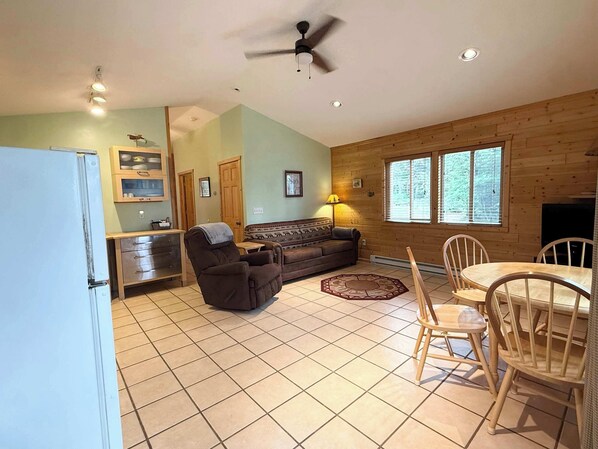 Un espacio habitable compacto con kitchenette, sofá, mesa de comedor con sillas y ventilador de techo.