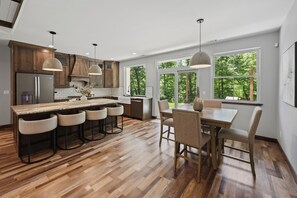 A modern kitchen with a central island, bar stools, and a dining table with chairs.