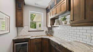 Una cocina con gabinetes de madera, azulejos tipo metro blancos y un ventanal con vistas a la vegetación.