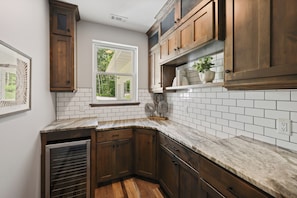 A kitchen with wooden cabinets, white subway tiles, and a window overlooking greenery. - Luxury Woodland Retreat Near Gull Lake, championship golf & Downtown Nisswa (Nisswa)