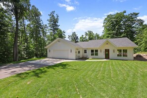 A two-story house with a garage, a front porch with chairs, and a well-maintained lawn. - Luxury Woodland Retreat Near Gull Lake, championship golf & Downtown Nisswa (Nisswa)
