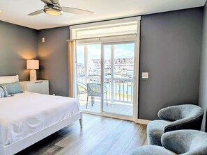 A bedroom with a bed, a chair, a balcony with a view, and a ceiling fan. - 22 South Shore Drive Ext - South Shore Marina (Bethany Beach)