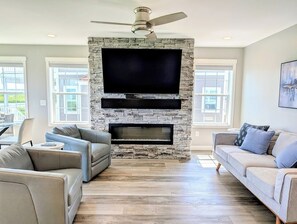 Een woonkamer met een stenen open haard, een flatscreen televisie en twee banken.