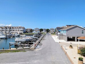 A marina with boats docked, a road leading to a building, and residential houses in the background. - 22 South Shore Drive Ext - South Shore Marina (Bethany Beach)