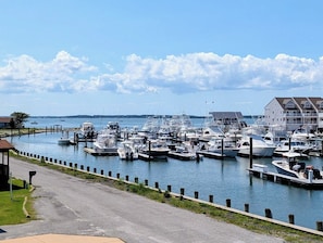 A marina with multiple boats docked, a clear sky, and a building with a balcony on the right. - 22 South Shore Drive Ext - South Shore Marina (Bethany Beach)