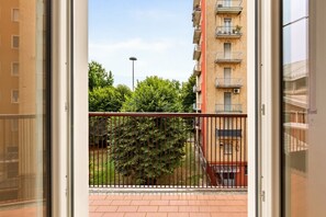 A view from a balcony with a metal railing, a building with multiple balconies, and a tree in the foreground. - Authentic North Milan · Metro M3 · Park · A/C · Self-check-in (Milano)