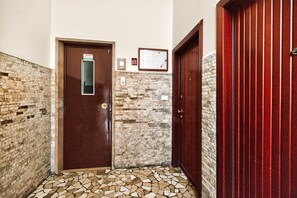A hallway with a brown door, a wall-mounted light switch, and a framed certificate. - Authentic North Milan · Metro M3 · Park · A/C · Self-check-in (Milano)