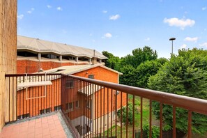 Un bâtiment à la façade en briques, doté d’un balcon avec une rambarde en métal, et un ciel dégagé.