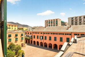 A courtyard with buildings, some with balconies, and a mountain in the background. - Spacious and bright penthouse, ideal for up to 7 people (Genova)