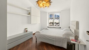 Ein modernes Schlafzimmer mit Bett, Nachttischen, einer Hängelampe und einem Fenster mit Blick.