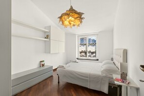 A modern bedroom with a bed, bedside tables, a hanging light fixture, and a window with a view. - Spacious and bright penthouse, ideal for up to 7 people (Genova)