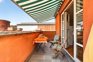 A small balcony with a table, chairs, and a fruit bowl. - Spacious and bright penthouse, ideal for up to 7 people (Genova)