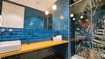Un bagno con una parete rivestita in piastrelle blu, un piano d'appoggio in legno, un lavandino bianco e un box doccia in vetro.