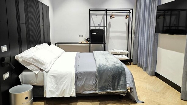 Ein modernes Schlafzimmer mit einem Bett, Nachttischen, einem Kleiderschrank und einem Fernseher.