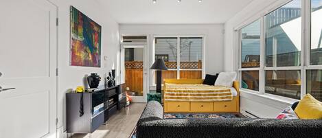 Un dormitorio moderno con cama, cómoda y ventanas amplias.