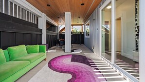 Un interior moderno con techo de madera, un sofá verde y una alfombra estampada.