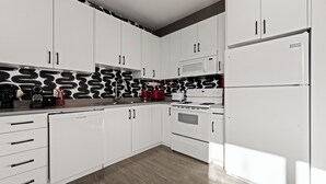 Una cocina moderna con alacenas blancas, microondas, estufa y lavavajillas.