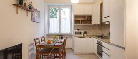 Una cocina compacta con armarios blancos, microondas y horno empotrado.