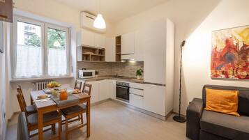 Een moderne keuken met witte kasten, een eettafel met stoelen en een bank in de woonkamer.