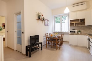 A compact living space with a dining area, kitchen, and a TV on a stand. - STRAMBIO, 8 – Smart Stay in Milan (Milano)