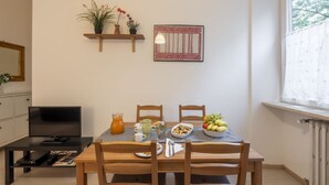 A dining area with a table set for two, a television, and a window with a view of trees. - STRAMBIO, 8 – Smart Stay in Milan (Milano)
