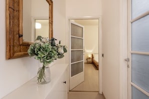 A hallway with a mirror, a vase with flowers, and a door leading to a room. - STRAMBIO, 8 – Smart Stay in Milan (Milano)